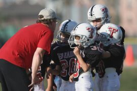 Coach and kids in football uniforms