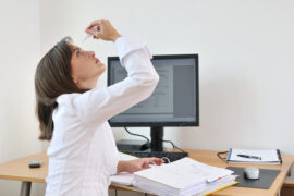 Woman adding eye drops at a computer work station
