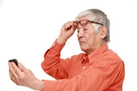 Man lifting glasses looking at phone screen