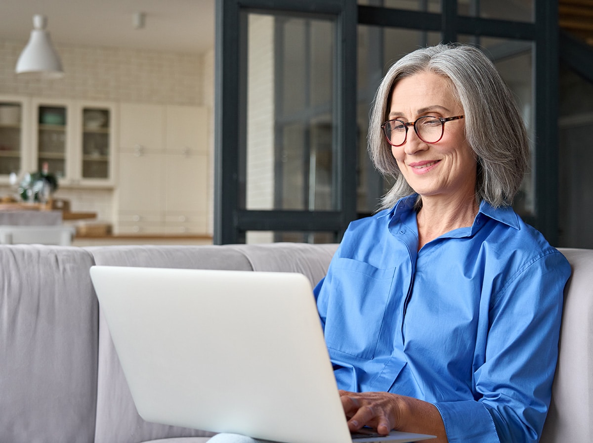 mature casual businesswoman on a couch working in a laptop